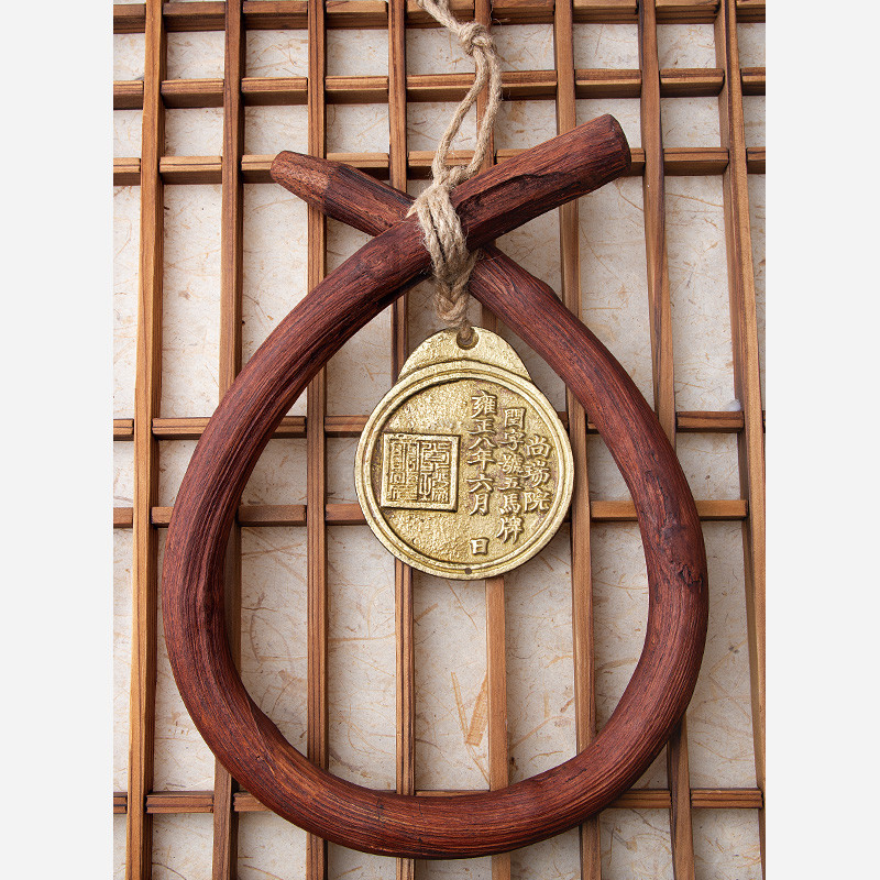 나무로 만든 갈색 고리와 황금색 금속제로 구성된 전통 마패 장식, 한자 음각 문양과 거친 질감이 특징인 장식품.