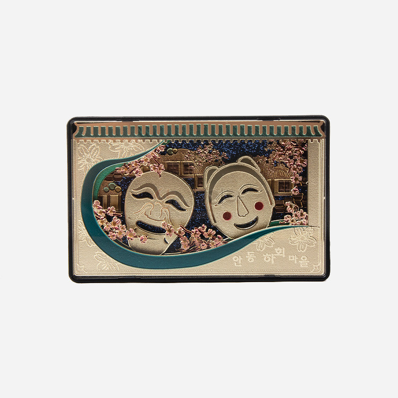 금속 재질 위에 하회탈과 안동 하회마을 전경을 부조 기법으로 표현하고, 분홍색 꽃문양과 녹색 곡선 장식이 어우러진 직사각형 마그넷.