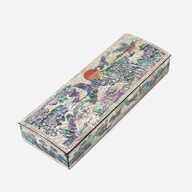 자개 상감 기법으로 학과 구름, 해 문양을 정교하게 표현한 직사각형 필함 형태, 오팔빛 녹색·보라색이 어우러진 옻칠 공예품.