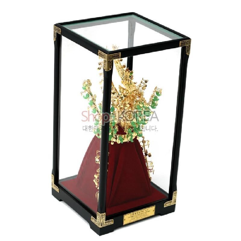 금속 재질로 표현한 금색 천마총 금관 모형과 녹색 옥 장식, 붉은 비단 받침 및 유리 장식 케이스가 조화를 이룬 장식품.