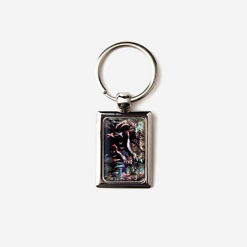 금속 사각 프레임에 자개 상감 기법으로 표현된 송학과 자연 풍경 문양, 오묘한 보라·초록 계열 색감이 돋보이는 열쇠고리.