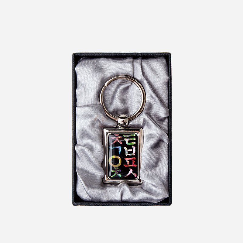 자개 상감 기법으로 형형색색 한글 문양을 넣은 사각 금속 테두리 열쇠고리. 자개 상감 기법으로 형형색색 한글 문양을 넣은 사각 금속 테두리 열쇠고리.