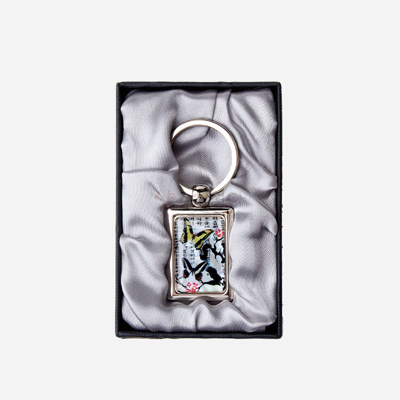금속 사각 테두리에 자개 상감 기법으로 매화와 나비 문양을 넣은 화이트·블랙·옐로 포인트 색상의 열쇠고리.