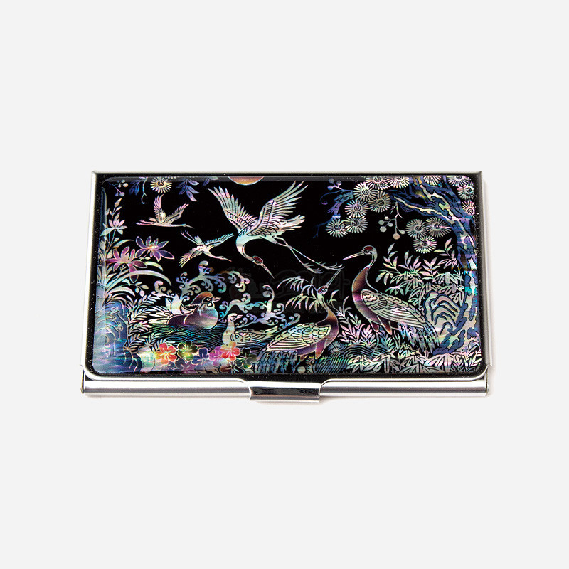 검은 바탕 위 자개 상감 기법으로 학과 소나무, 연꽃을 섬세하게 표현한 금속 명함집.