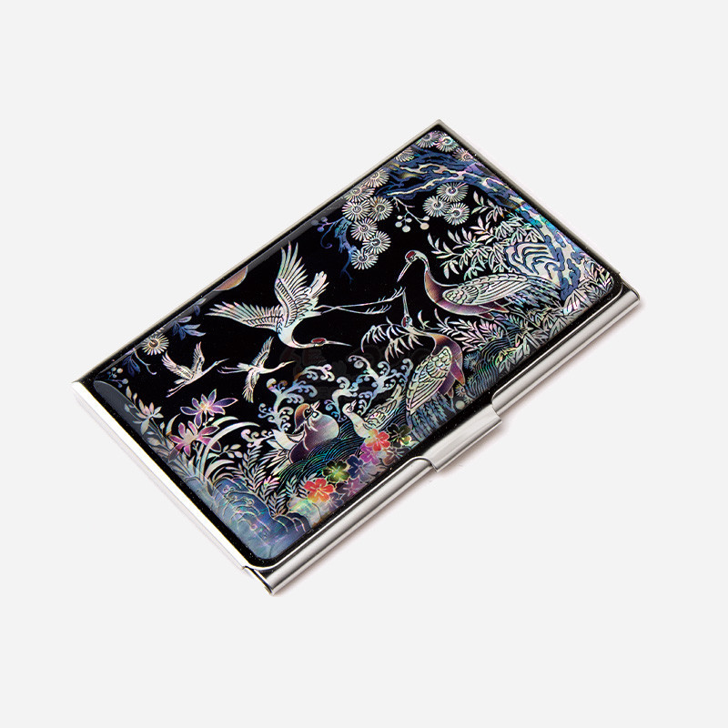 검은 바탕 위 자개 상감 기법으로 학과 송학, 화조 무늬를 섬세하게 표현한 금속 테두리 명함집.