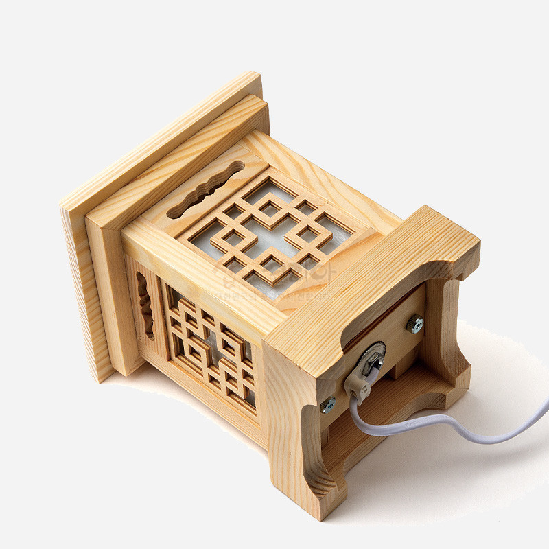 밝은 원목 재질에 완자문살을 정교하게 도안한 사각형 조립 구조의 전통 조명등.