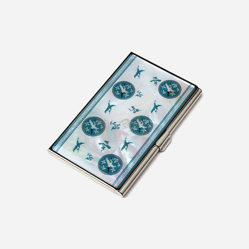 자개 바탕 위에 청자색 상감 운학문과 연속 문양 테두리가 더해진 금속 명함집.