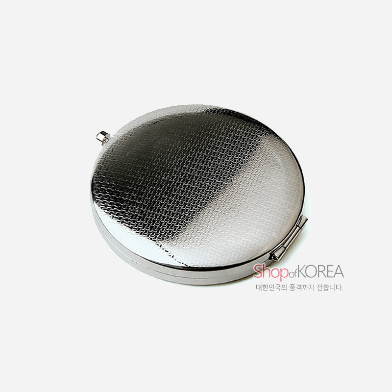 은색 금속 재질의 원형 손거울, 표면 전체에 미세한 격자 패턴 양각이 들어간 디자인의 거울.