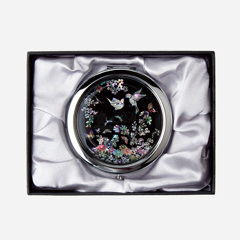 검은 옻칠 바탕에 자개 상감으로 화조도와 꽃문양을 섬세하게 표현한 금속 테두리 손거울.