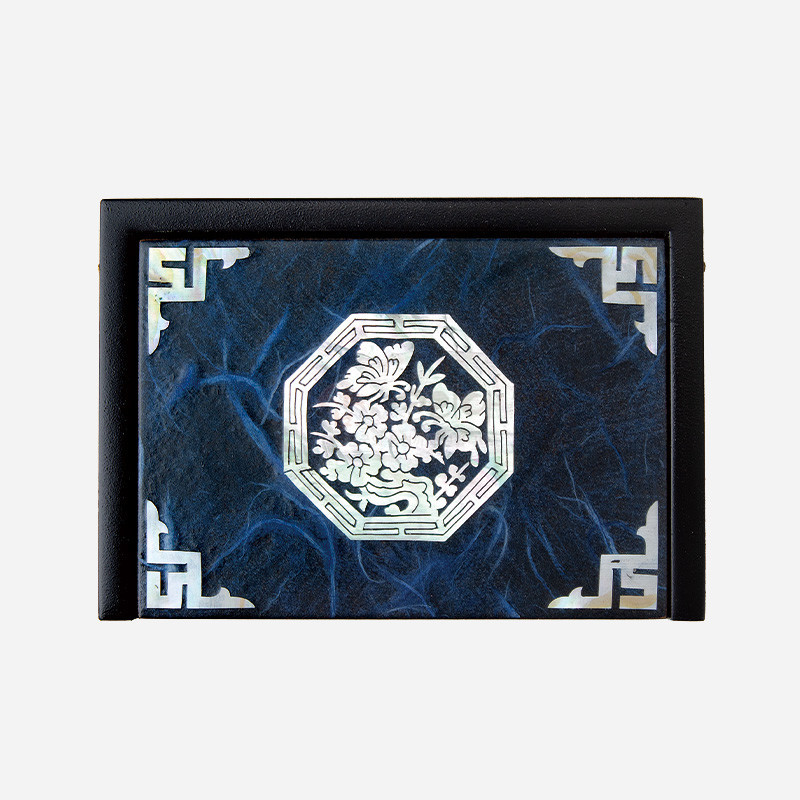 청색 한지 바탕 위 자개 상감으로 매화와 나비 문양을 넣고 모서리에 기하학적 자개 장식을 더한 나전칠기 명함함.