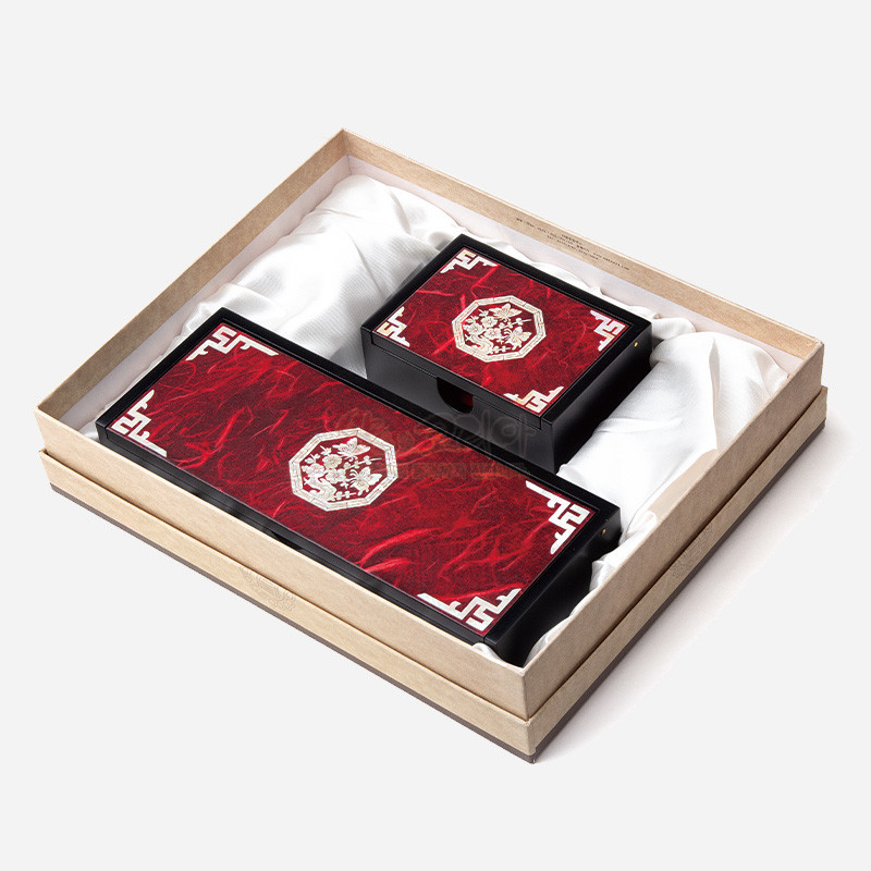 붉은 한지 배경 위 자개 매화문과 흰색 모서리 전통기하 문양이 장식된 필함과 명함함 세트.