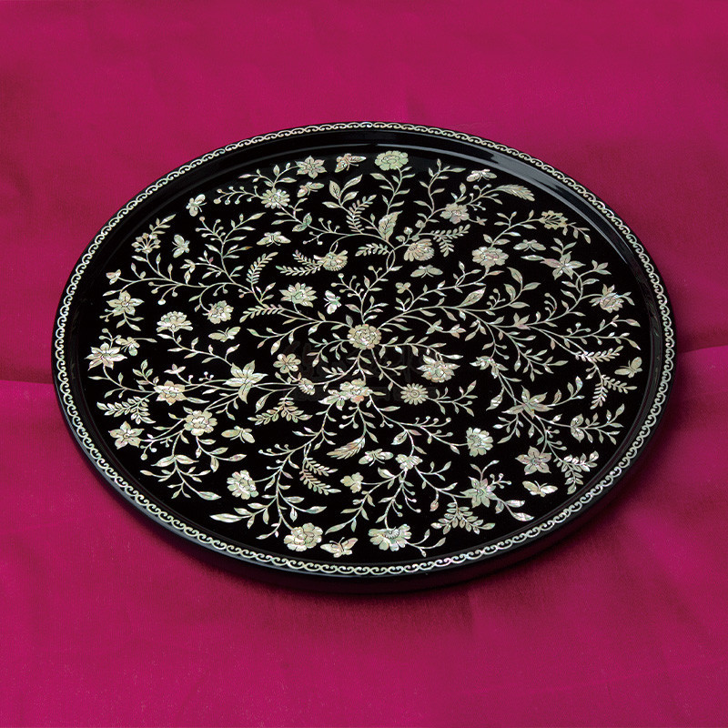 검은 옻칠 바탕 위에 자개 상감으로 섬세한 넝쿨과 꽃문양을 채운 원형 나전칠기 쟁반. 검은 옻칠 바탕 위에 자개 상감으로 섬세한 넝쿨과 꽃문양을 채운 원형 나전칠기 쟁반.