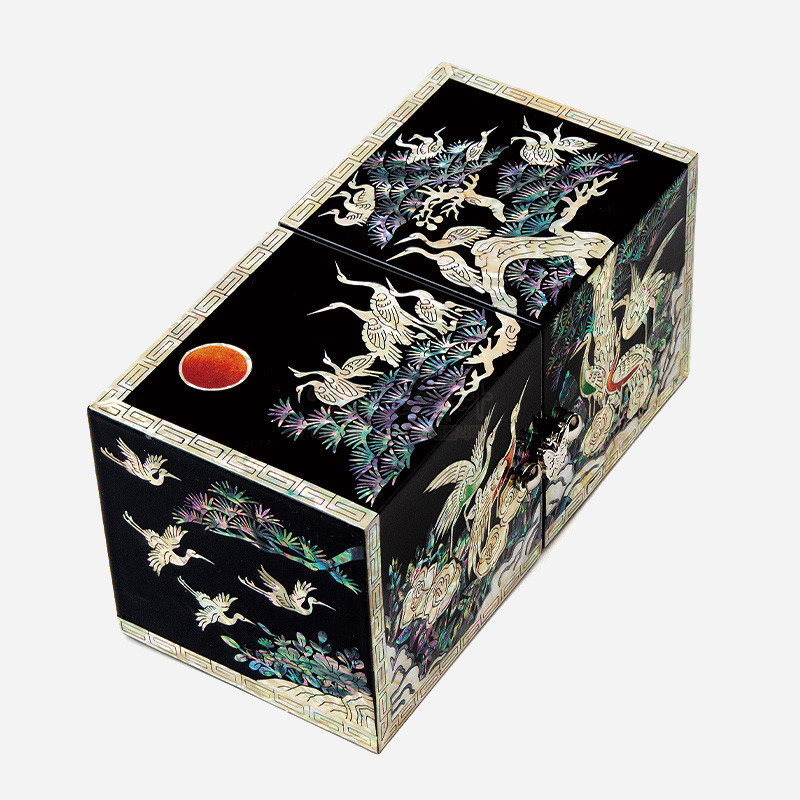 검은 옻칠 바탕에 자개 상감으로 송학도와 소나무, 붉은 해 문양을 섬세하게 표현한 쌍합.