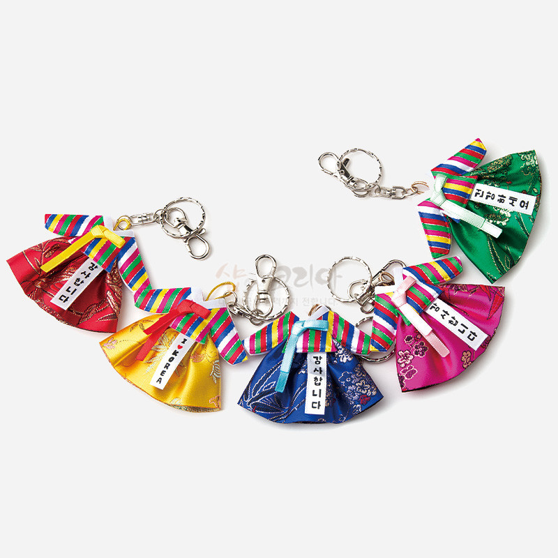 색동 고름과 비단 치마로 구성된 한복 모양 금속 열쇠고리, 다채로운 색상과 전통 문양 장식.