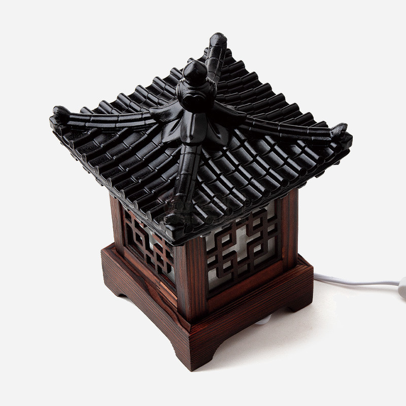 짙은 갈색 목재와 검은 기와 지붕, 창호에 정기와 완자문을 담은 전통 좌등.