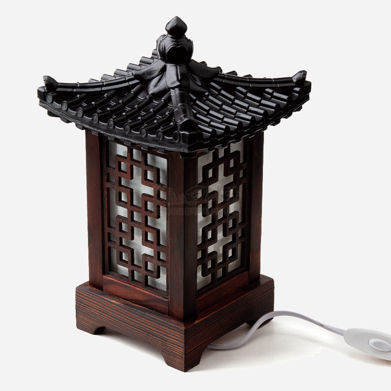어두운 목재와 흑색 기와 지붕 형태, 반투명 창에 완자문이 장식된 전통 미니 좌등.