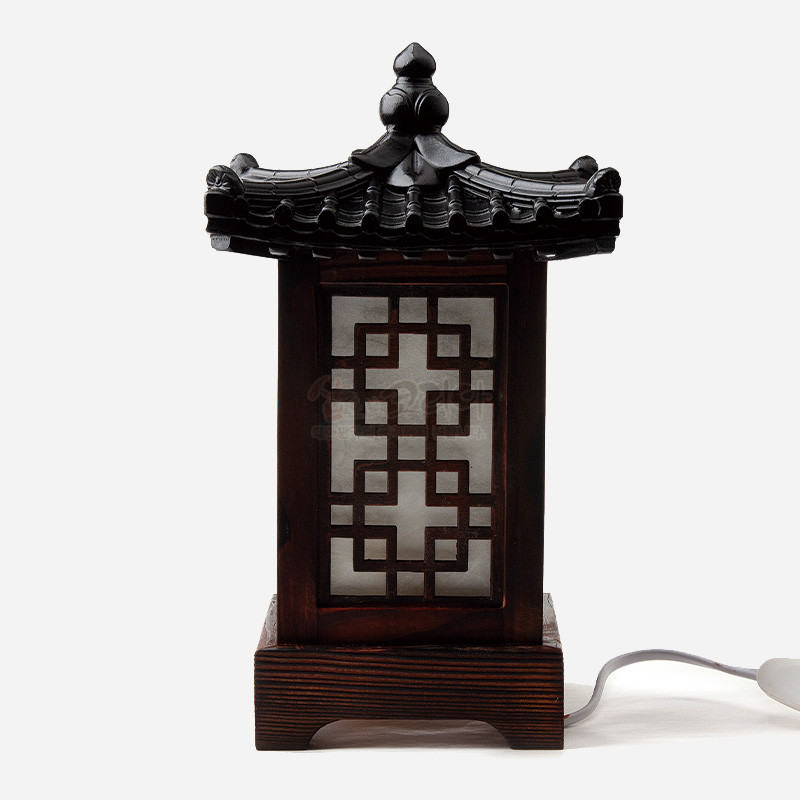 어두운 목재와 기와 지붕 형상의 상부, 반투명 창호지에 완자문 격자무늬가 더해진 전통 미니 좌등.