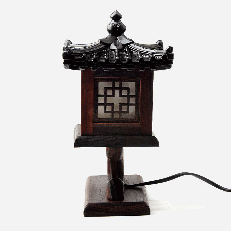 짙은 갈색 원목으로 제작된 전통 누각 형상의 소형 좌등, 완자문 창살과 기와지붕 세공이 특징인 조명기.