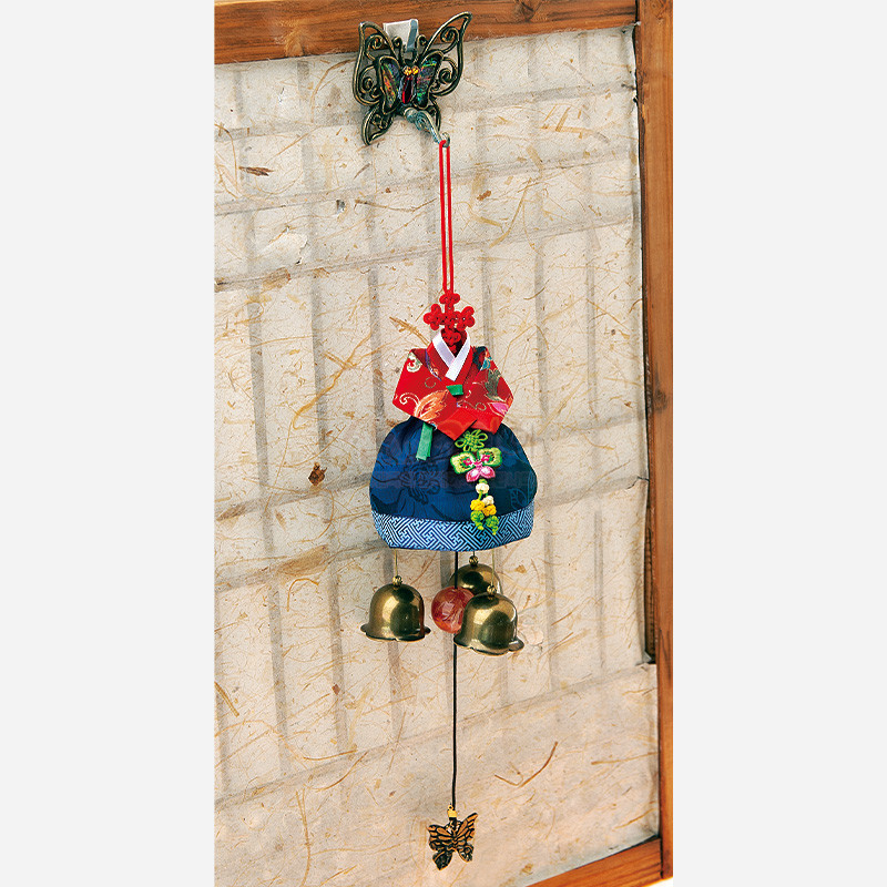 적색 비단 저고리와 청색 치마로 구성된 한복 모양 패브릭 문종, 매듭 장식과 나비·꽃 자수, 금속 종과 나비 펜던트가 달린 장식.