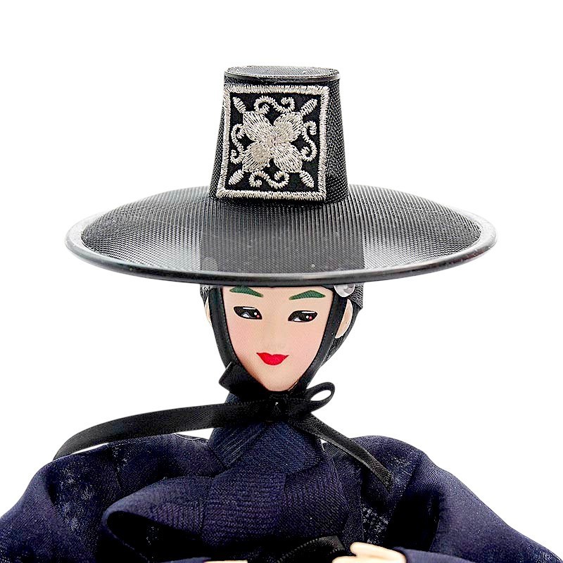 검은색 갓과 사각 관 모양 장식 위 은색 자수 문양이 돋보이는 전통 한복 인형.