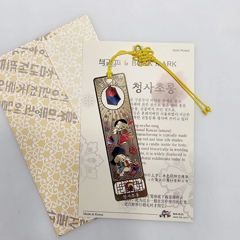 금장 금속 소재에 청사초롱과 한복 인물 문양을 채색하고 노란 전통 매듭 끈이 달린 직사각형 책갈피.