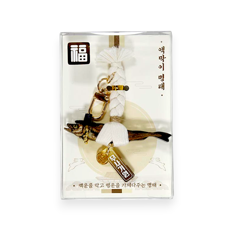 흰색 매듭 끈과 갓을 쓴 명태 조형, 금속 장식과 한글 문자 장식이 조화된 전통 풍습 장식품.