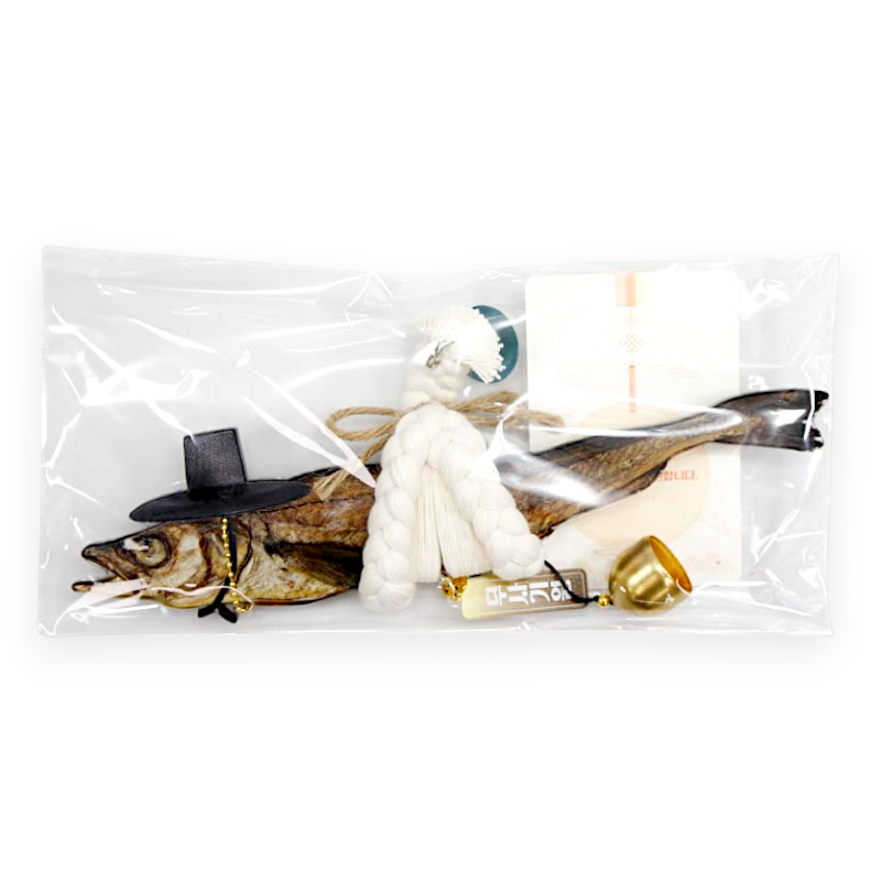 건조 명태에 검은색 미니 갓 장식과 흰색 삼끈 술 장식, 황금색 방울 장식이 함께 구성된 전통 액막이 장식품.