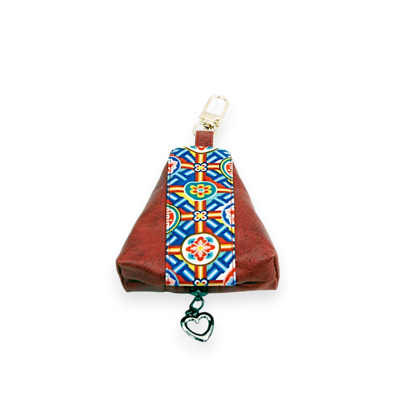 적색 천 소재에 청·황·녹 단청 기하학·연꽃 문양 배색이 더해진 동전지갑, 금속 고리와 하트 장식 연결 디자인.