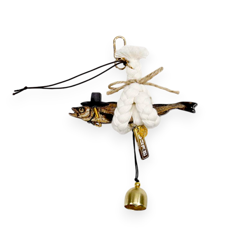 명태 모형과 흰색 꼬임 끈, 금속 종과 장식패가 어우러진 전통풍 액막이 장식품.