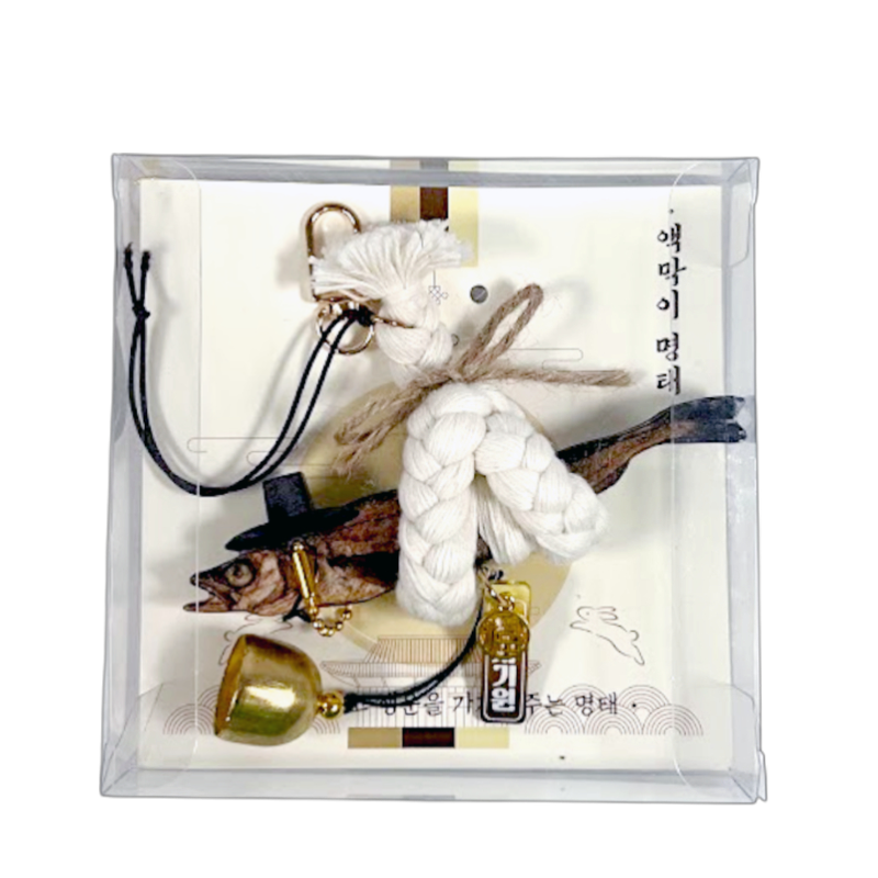 건조 명태에 검은색 갓 장식과 흰색 면 노끈 매듭, 금속 종과 펜던트가 어우러진 전통 액막이 장식품.