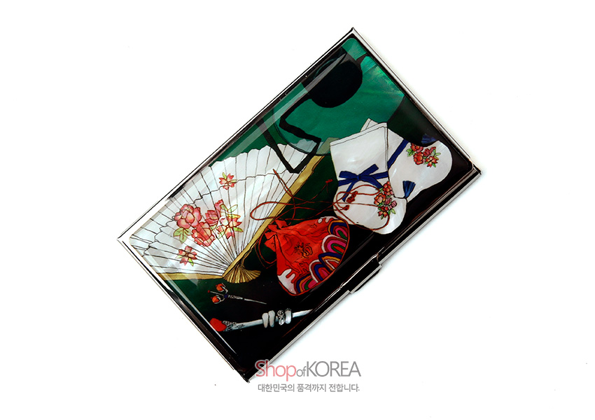 [텍스트: Shop of KOREA, 대한민국의 품격까지 전합니다.] 자개 광택 금속 명함집 위에 꽃무늬 부채와 전통 버선, 붉은 복주머니, 먹물 붓이 다채로운 색감으로 인쇄된 디자인