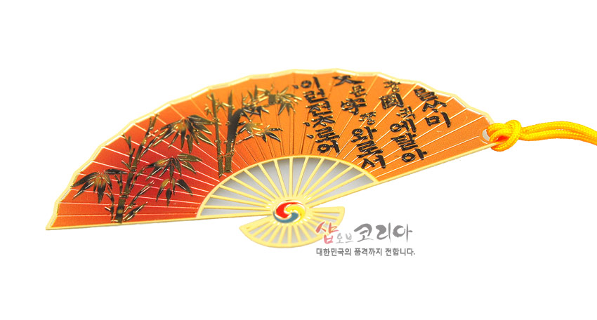 [텍스트: 사람에게는 말씀이 있고 그 말씀은 곧 마음에 달아 있는 것이다.] 오렌지색 반달 부채형 금속 책갈피에 대나무 문양과 태극 문양, 노랑 전통 매듭 끈 장식 이미지 설명