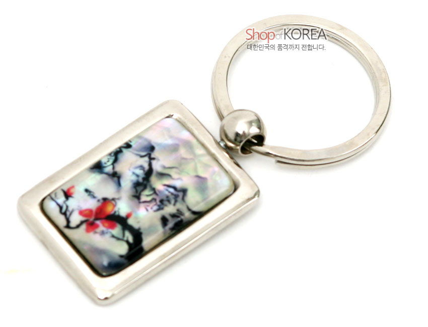 [텍스트: Shop of KOREA 대한민국의 품격까지 전합니다.] 사각 금속 테두리 안에 채색 자개를 상감하여 은은한 오색 광택 위 산수도와 붉은 매화 문양을 표현한 열쇠고리 이미지 설명