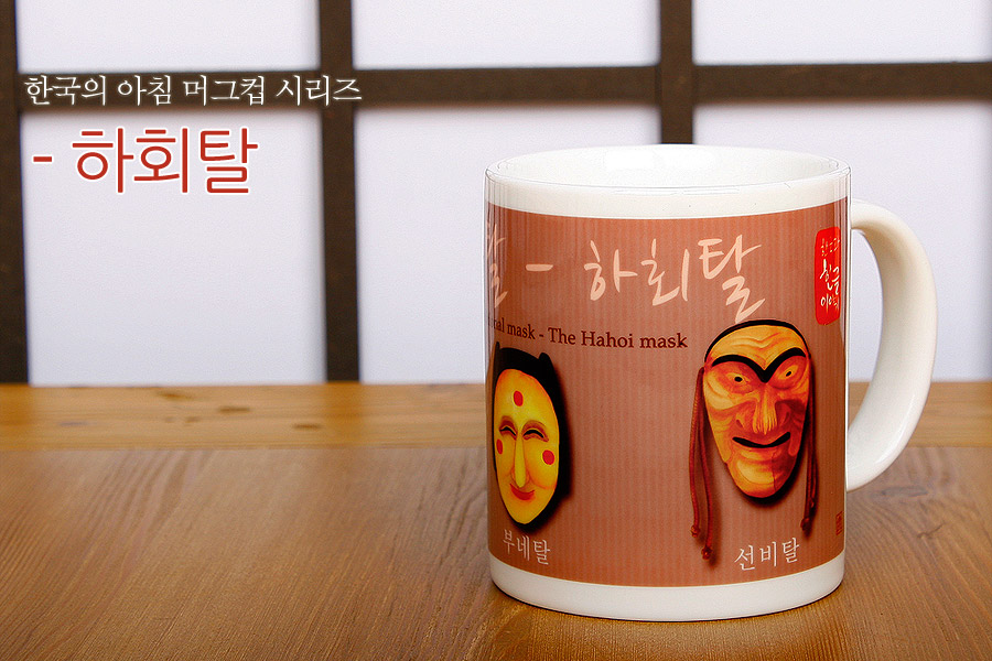 [텍스트: 한국의 아침 머그컵 시리즈 - 하회탈, Traditional mask - The Hahoi mask, 부네탈, 선비탈] 흰 도자기 머그컵에 갈색 바탕과 하회 부네탈·선비탈 일러스트, 한글 캘리그래피가 조화된 디자인