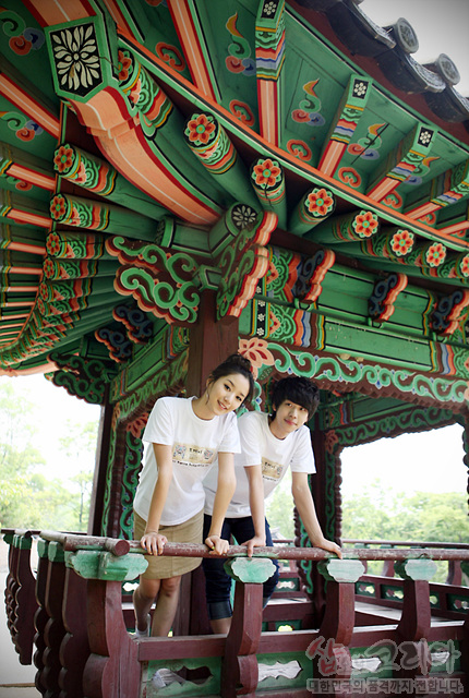 [텍스트: 샵오브코리아 대한민국의 전통자개공예입니다] 흰색 면 티셔츠의 3D 입체 발포 도깨비 문양과 단청 채색 전통 누각의 화려한 기둥·공포 조화 이미지 설명