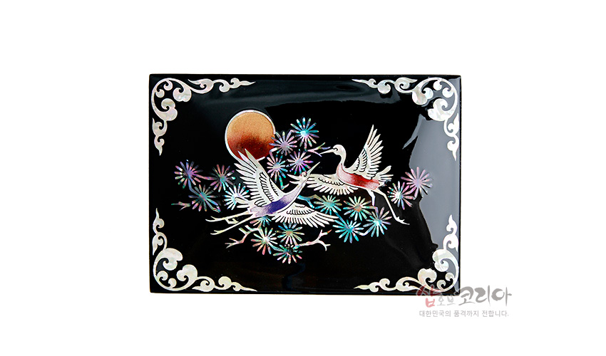 [텍스트: 샵오브코리아 대한민국의 품격까지 전합니다] 흑색 옻칠 바탕 위 자개 상감 기법으로 해와 송학, 채색 꽃문양을 표현한 직사각 명함함 디자인