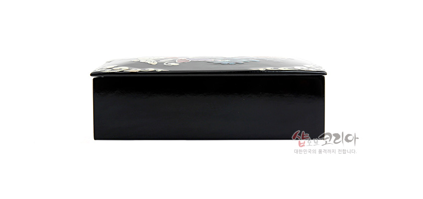 [텍스트: 샵오브코리아 대한민국의 품격까지 전합니다.] 흑색 옻칠 표면 위 자개 상감으로 송학과 꽃문양이 채색된 직사각형 명함함 측면 모습