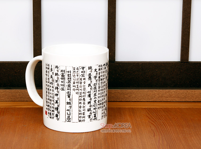 [텍스트: 훈민정음 언해 본문 글귀] 백색 도자 머그에 흑색 한자와 언해 글씨, 붉은 낙관이 세로 배열된 전통 서체 디자인 컵 이미지