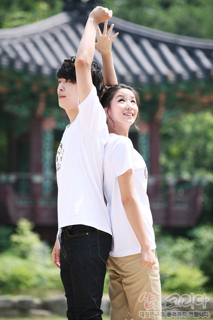 [텍스트: 샵오브코리아 대한민국의 전통문화를 전합니다] 전통 정자를 배경으로 한글, 탈, 태극 문양이 발포 프린트된 흰색 면 티셔츠 착용 모습