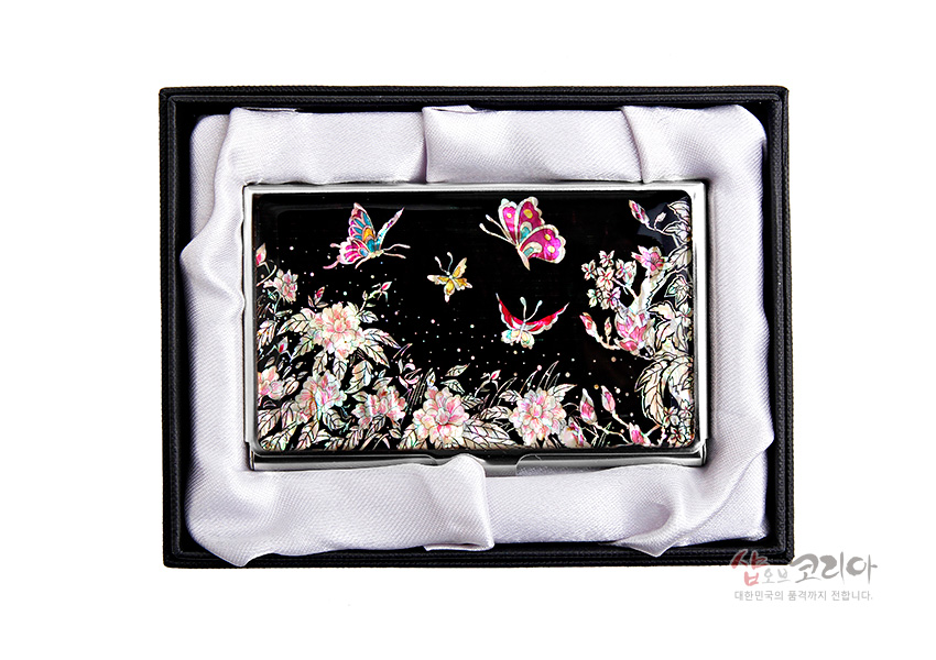 [텍스트: 샵오브코리아 대한민국의 품격까지 전합니다.] 흑색 옻칠 바탕 위 자개 상감으로 목단꽃과 나비 문양을 섬세하게 표현한 금속 명함집 구성