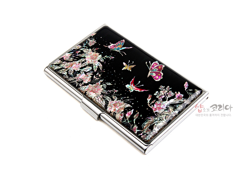 [텍스트: 샵오브코리아 대한민국의 품격까지 전합니다.] 흑색 옻칠 바탕 위 자개 상감으로 목단꽃과 다채로운 나비 문양을 섬세하게 표현한 금속 명함집 디자인