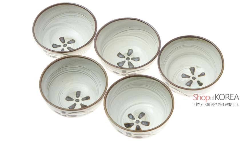 [텍스트: Shop of KOREA 대한민국의 품격까지 전합니다.] 연한 회백색 유약 위에 갈색 국화 문양과 테두리를 손그림 기법으로 장식한 도자기 소주잔 5종 세트 모습
