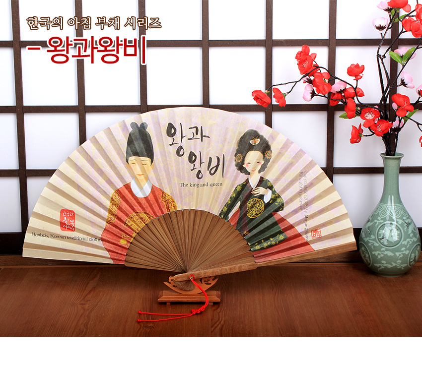 [텍스트: 한국의 아침 부채 시리즈 - 왕과왕비 / 왕과 왕비 / The king and queen / Hanbok, Korean traditional cloth] 한지 재질 수채화풍 왕과 왕비 문양, 나무 살대와 붉은 매듭 장식 전통 접이식 부채 이미지 묘사