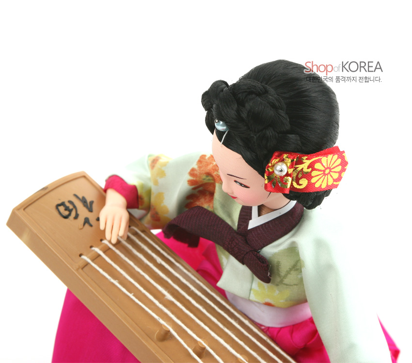 [텍스트: Shop of KOREA 대한민국의 품격까지 전합니다.] 분홍 비단 치마와 연두 저고리, 꽃무늬 자수 머리장식, 나무 재질 가야금을 섬세하게 표현한 한복 인형 모습