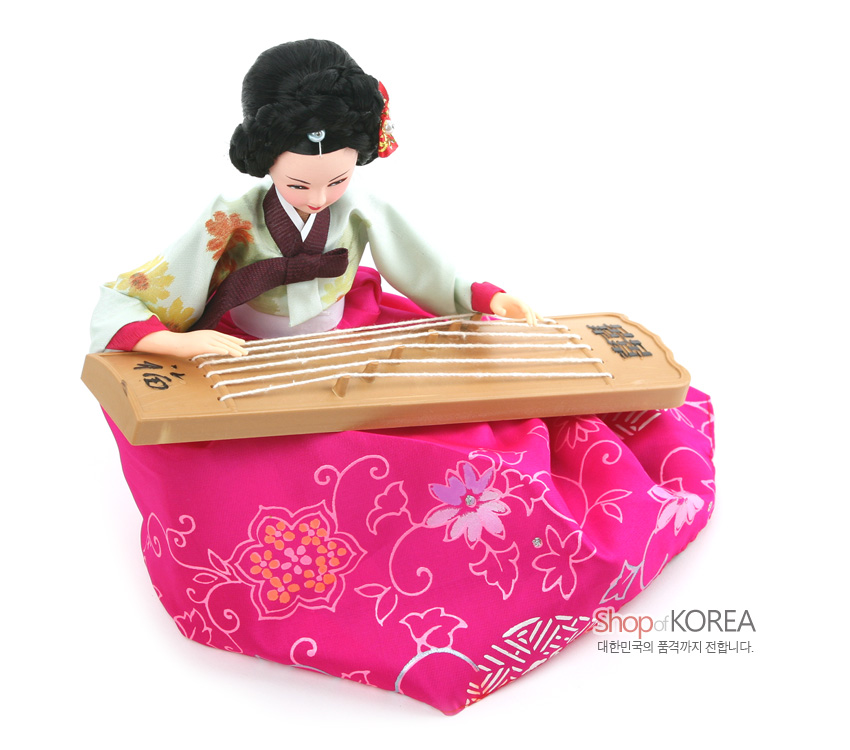 [텍스트: 福, shop of KOREA, 대한민국의 품격까지 전합니다.] 분홍색 꽃문양 비단치마와 연두 저고리를 입고 나무 가야금을 연주하는 전통 한복 인형 장식 이미지