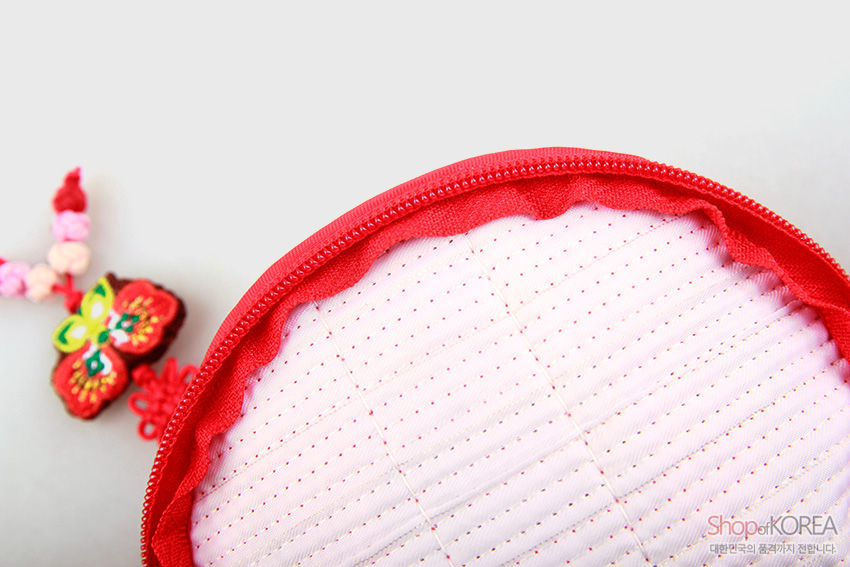[텍스트: ShopofKOREA 대한민국의 품격까지 전합니다.] 분홍 누비 비단 안감과 붉은 지퍼 마감, 전통 매듭과 나비 장식 디테일의 동전지갑 내부 모습