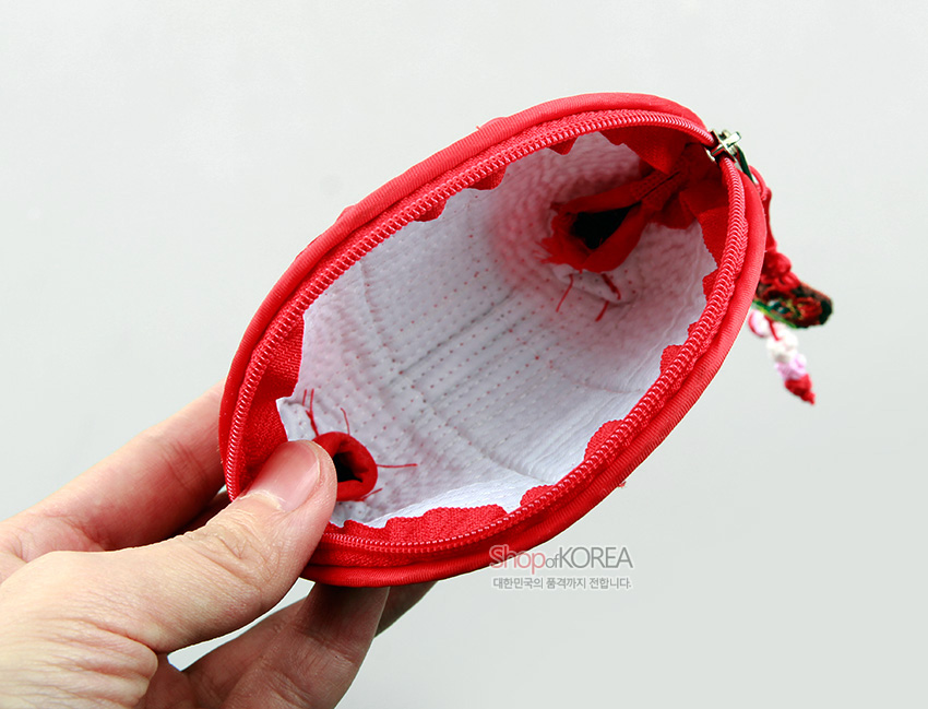 [텍스트: ShopofKOREA 대한민국의 품격까지 전달합니다] 붉은 비단 겉감과 흰색 누빔 안감, 지퍼 여밈과 매듭 장식이 더해진 반원형 동전지갑 내부 모습