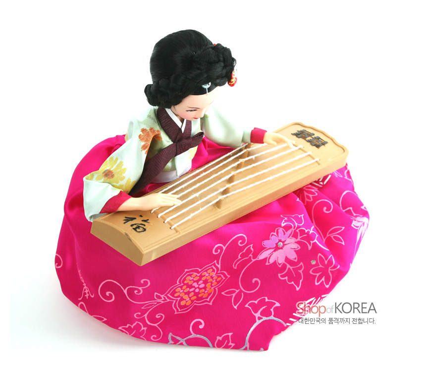 [텍스트: 福, shop of KOREA 대한민국의 품격까지 전합니다.] 분홍 비단 치마에 꽃·덩굴 무늬를 수놓은 한복 인형과 나무 재질 가야금을 연주하는 전통 악기 표현 인형 장식