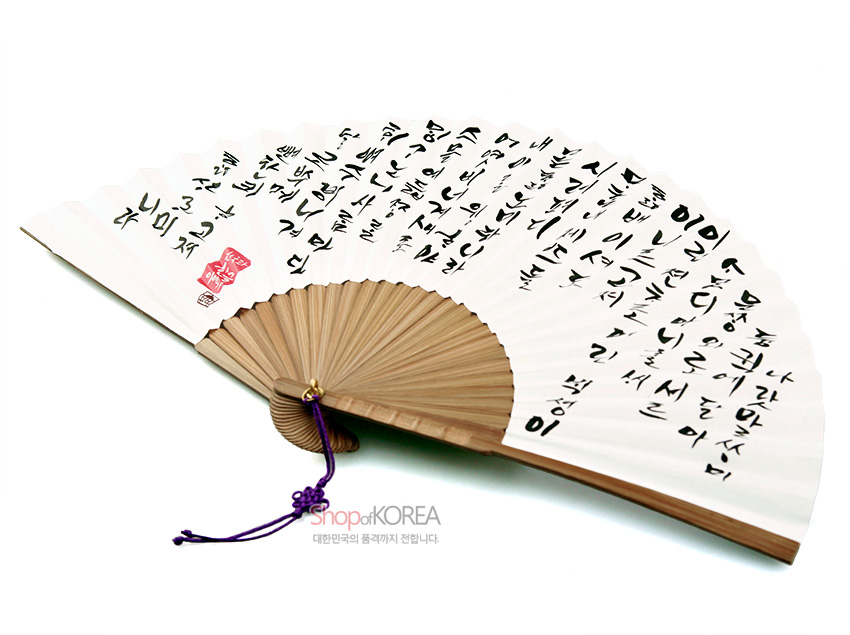 [텍스트: Shop of KOREA / 대한민국의 품격까지 전합니다] 흰 한지 위 검은 먹 훈민정음 캘리그래피와 붉은 전각 도장, 자연색 대나무 살과 자주색 매듭이 조화를 이룬 접이식 부채 디자인