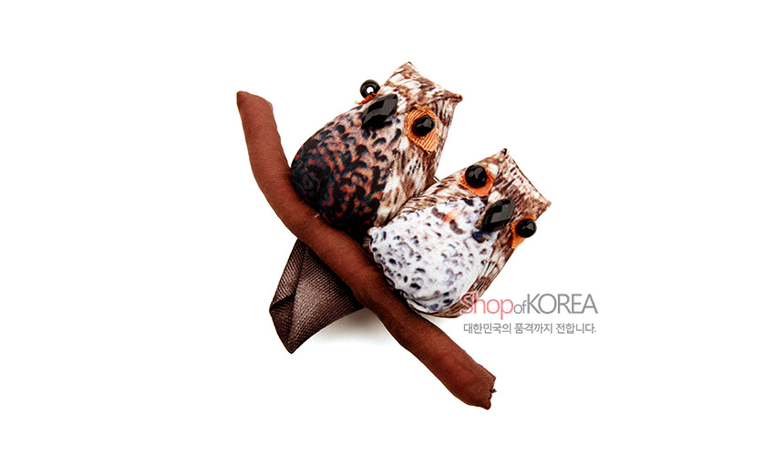 [텍스트: shopofKOREA 대한민국의 품격까지 전합니다.] 갈색 계열 패브릭으로 표현된 부엉이 두 마리 장식, 검은 보석 장식 눈과 가지 모양 누비 원단 조합 디테일 표현